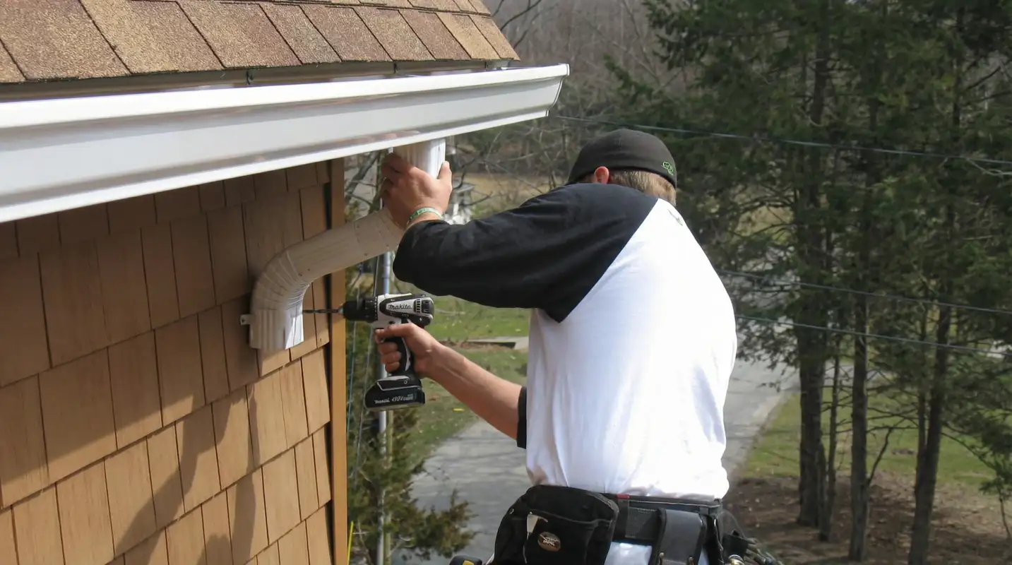 Professional contractor installing tan vinyl siding panels on a residential home exterior in Toledo, OH
